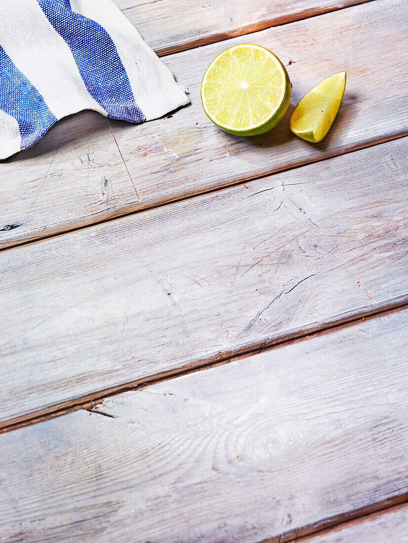 Halbe Limette und Schnitz auf Holztisch