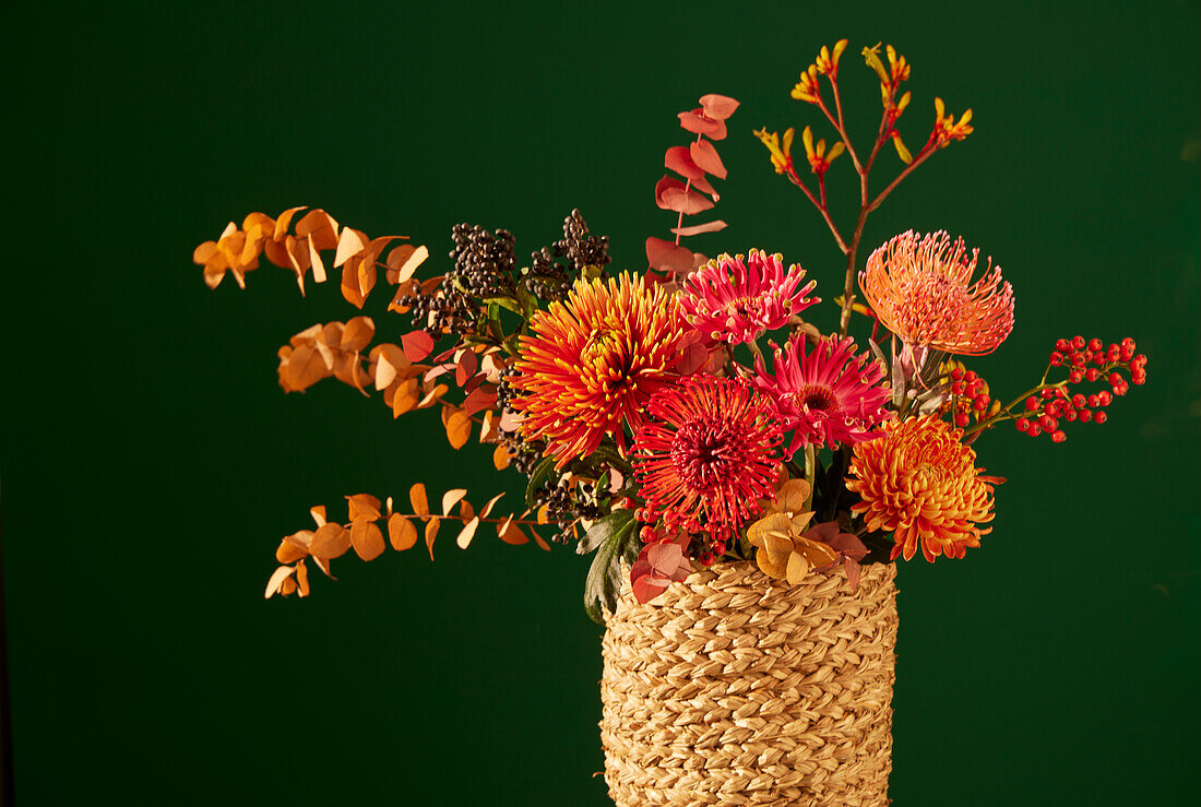 Autumn bouquet with chrysanthemums, eucalyptus and berries in a woven vase