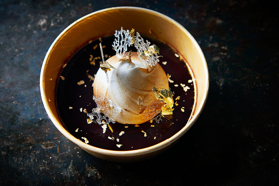 Baked Alaska with chocolate sauce and gold leaf