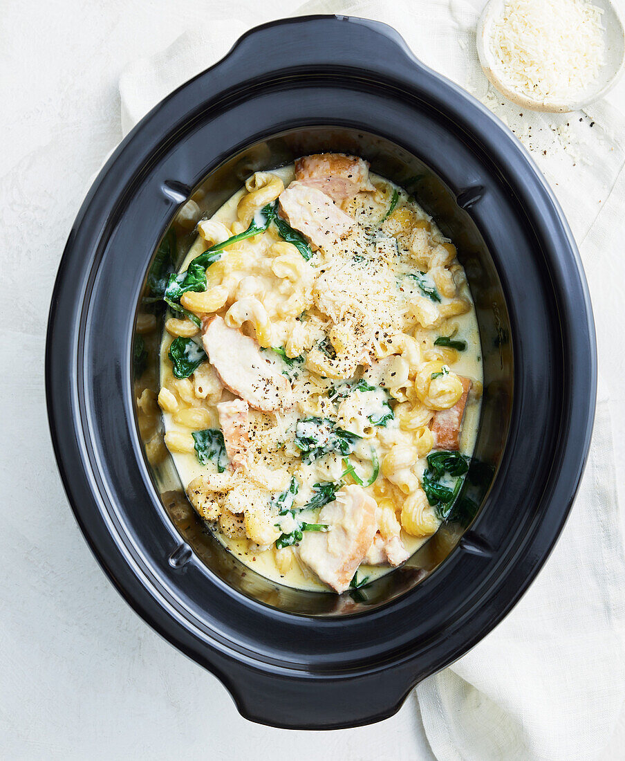 Creamy macaroni with chicken, cheese and spinach leaves