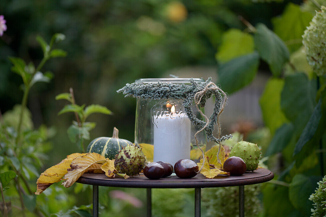 Windlicht mit Herz aus Heide auf herbstlich dekoriertem Tisch im Garten