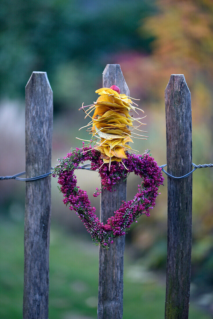 Heather heart with leaves lined up on a wooden fence, autumn decoration