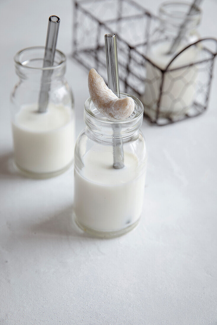 Milch in Gläsern mit Strohhalmen und Cashewkeksen