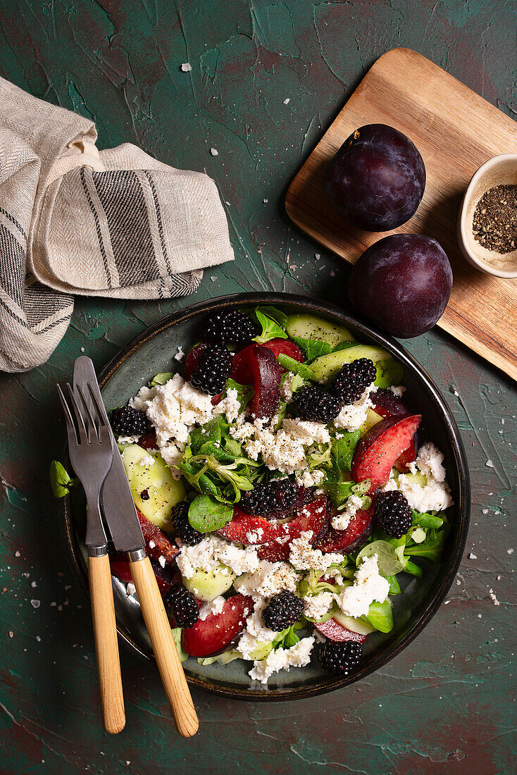 Salad with cucumber, plums, cheese and blackberries