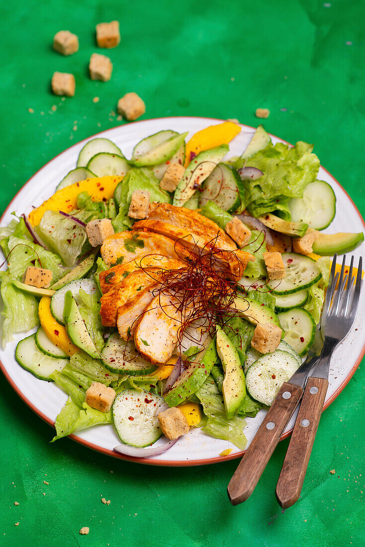 Salat mit Hähnchenbrust, Gurke, Mango und Croûtons