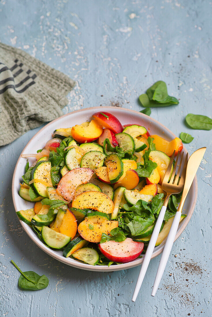 Spinach salad with cucumber, courgette and peaches