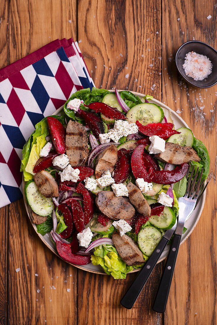 Salad with grilled beef, plums, red onions and cucumber