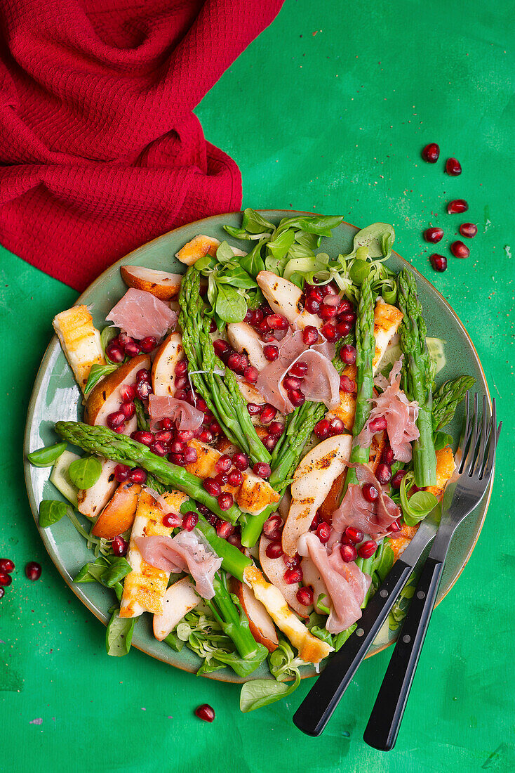 Salad with halloumi, green asparagus, pear, ham and pomegranate