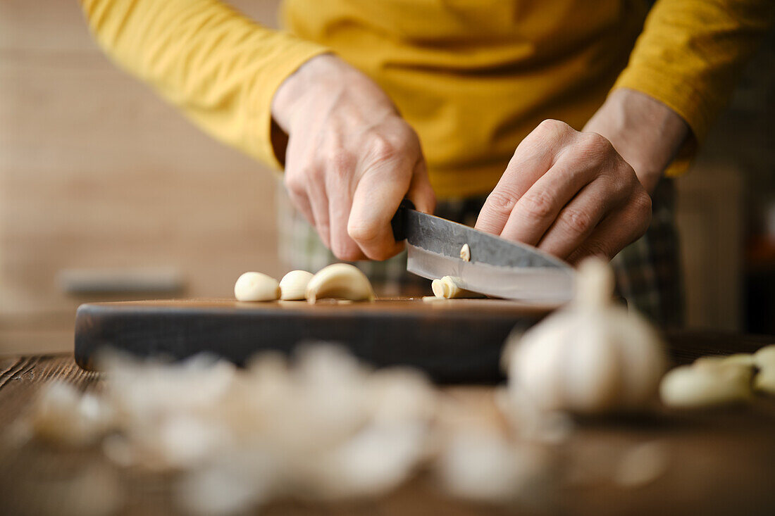 Knoblauchzehen auf Holzbrett schneiden