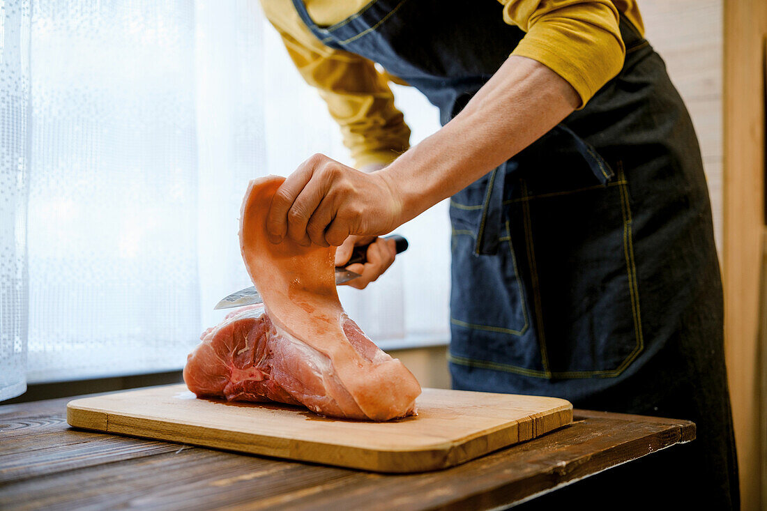 Cut off the rind of a raw pork shoulder