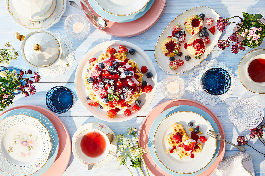 Waffles with berries and whipped cream, miniature sugar cakes with berries