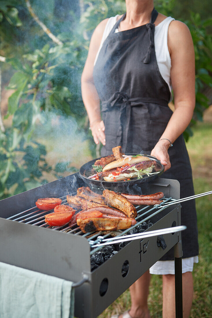 Frau grillt Hot Dogs und Spareribs