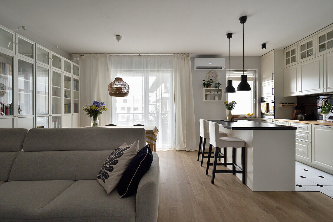 Open-plan living room with kitchen and dining area in cream and grey tones