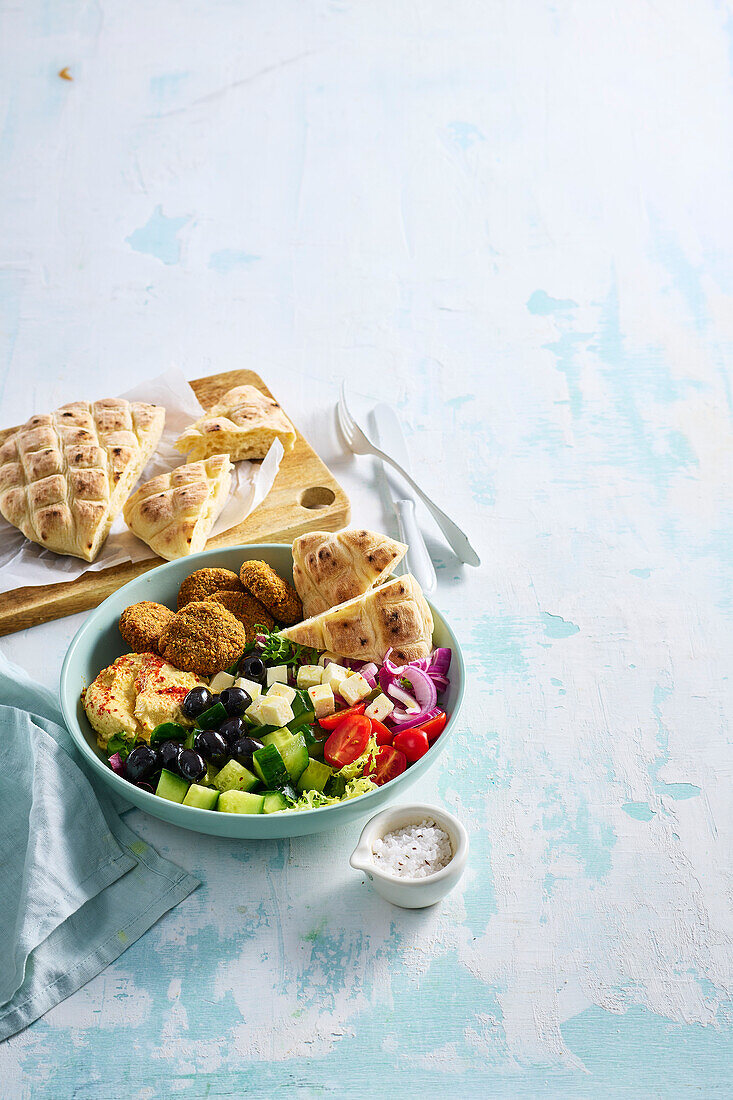 Falafel salad with vegetables, hummus, olives and flatbread