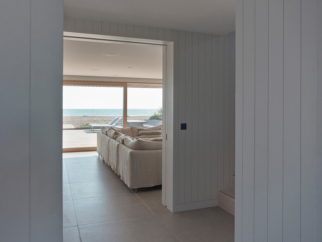 Open-plan living room with sea view and light-coloured wooden walls