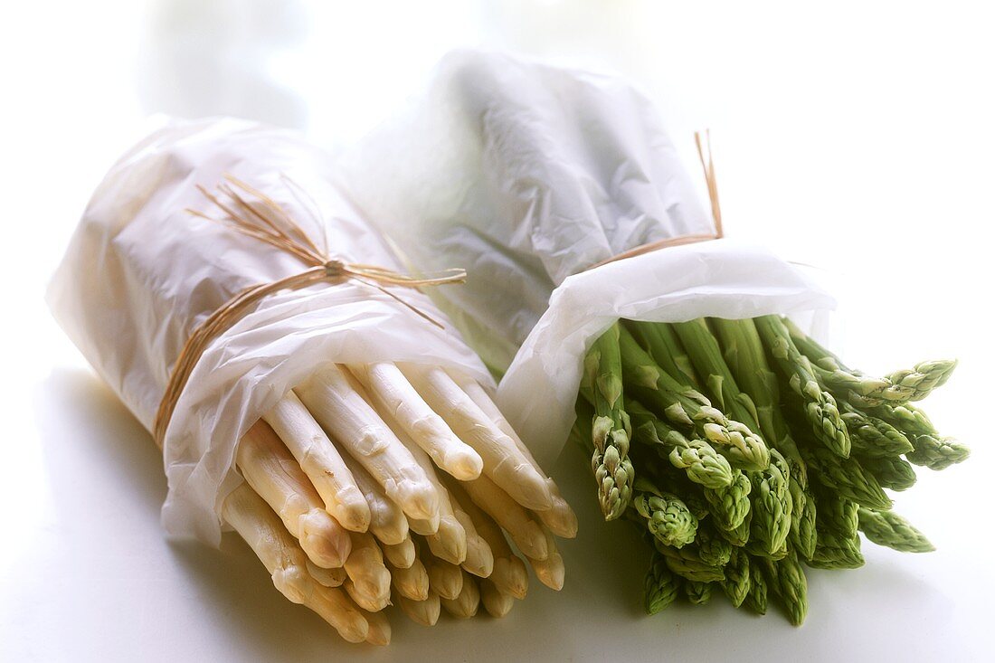 Bundles of green and white asparagus wrapped in paper