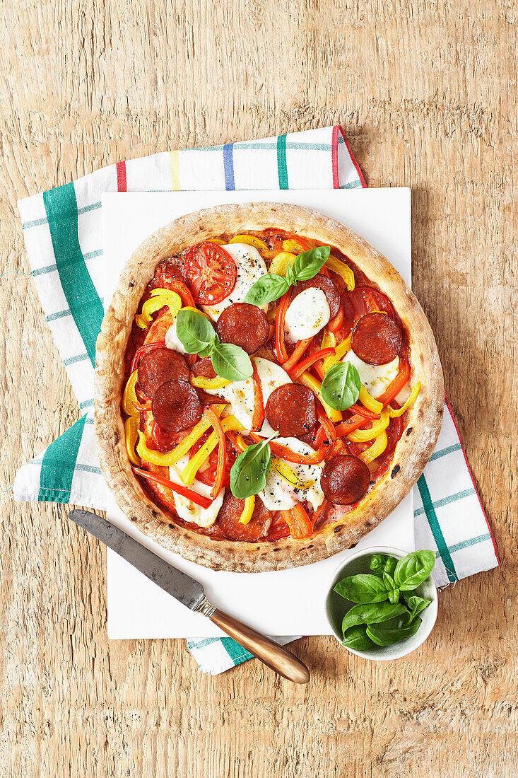 Pepperoni pizza with peppers, mozzarella and basil