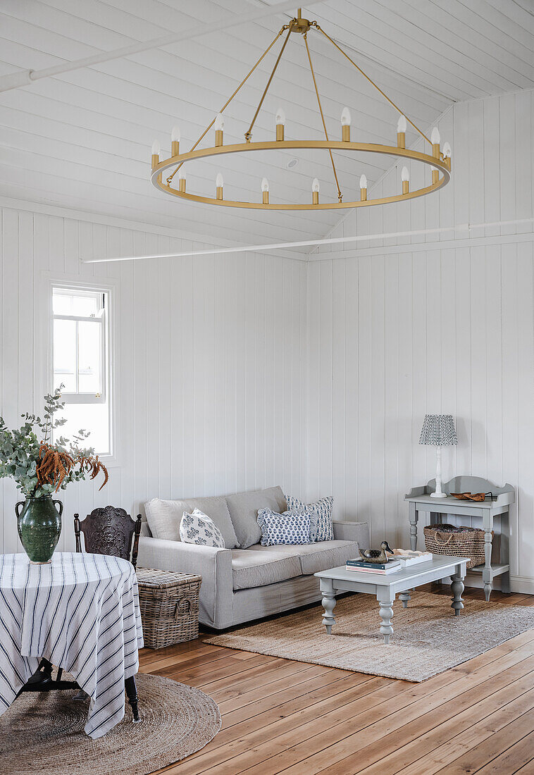 Living room in white with grey furniture and large chandelier