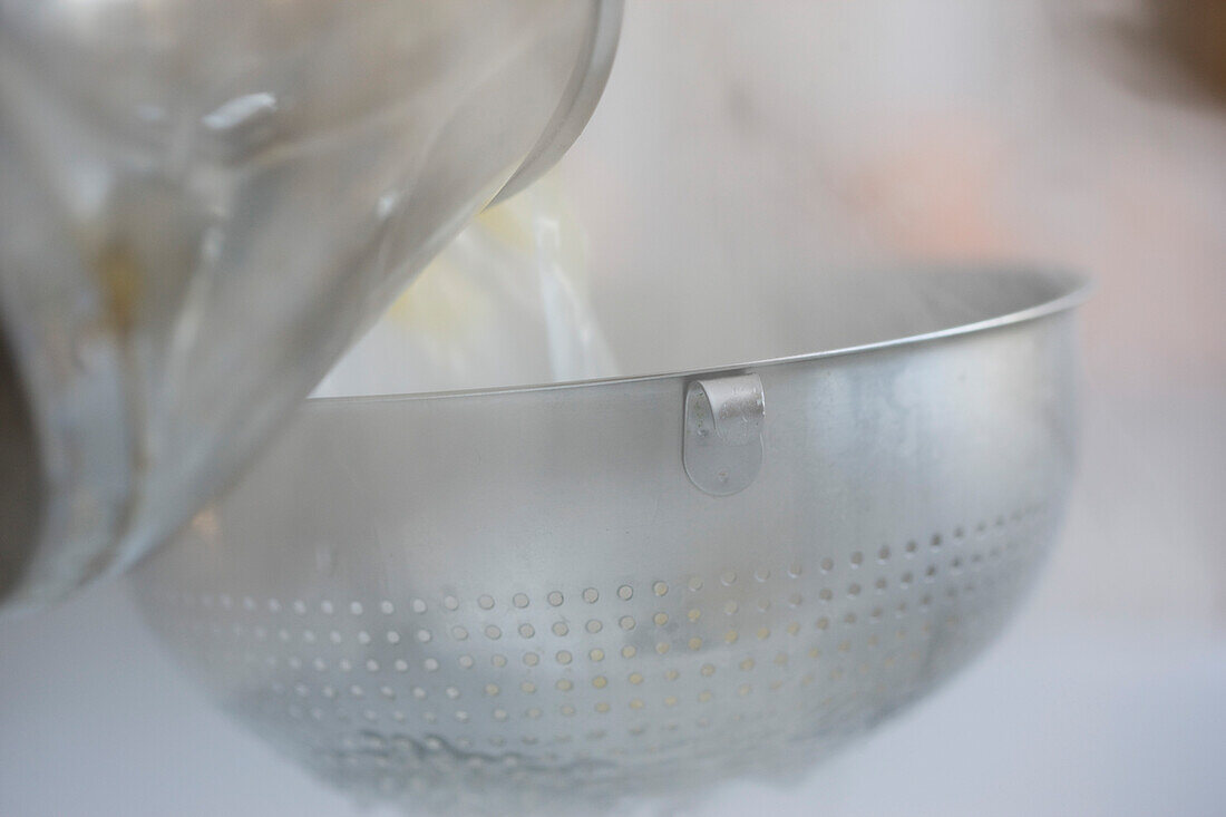 Pouring boiling water and pasta into a colander