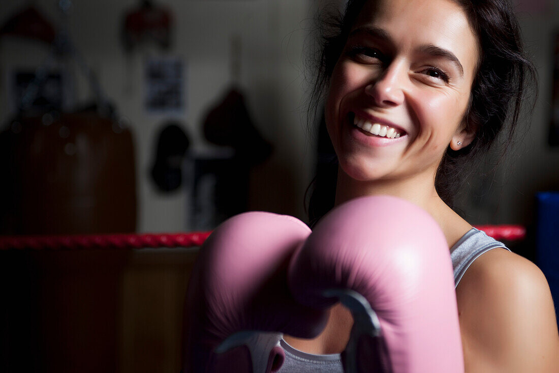 Woman wearing pink boxing gloves smiling