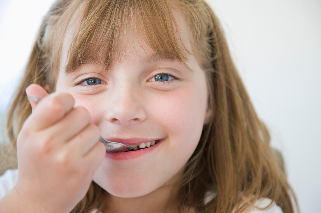 Young Girl Eating with Dessert Spoon