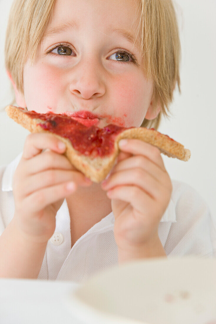 Junge isst Marmelade auf Toast