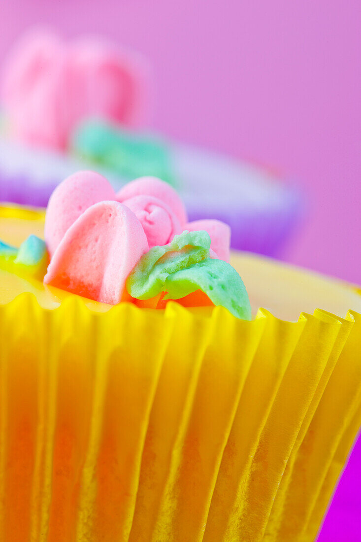 Hellgelber Cupcake mit pastellrosa Blumendekoration