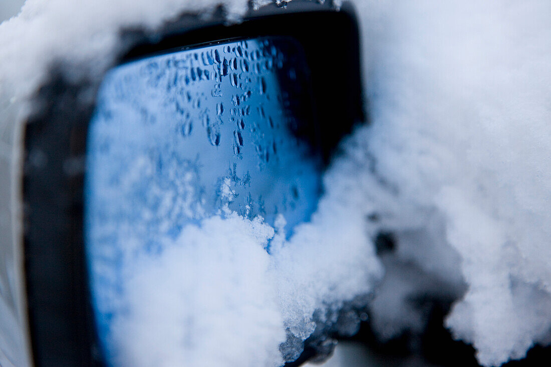 Car wing mirror covered in snow