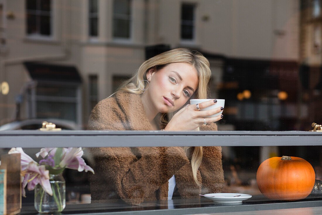 Young Woman Sitting in Cafe Having Coffee