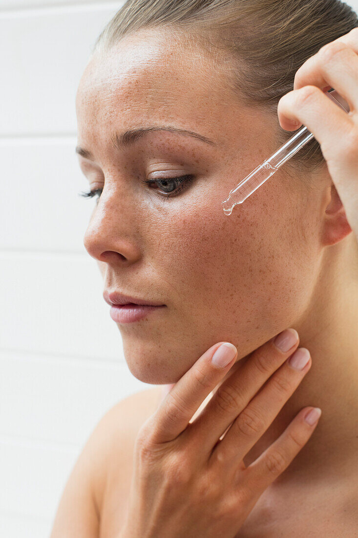 Beauty Portrait of Woman Applying Serum