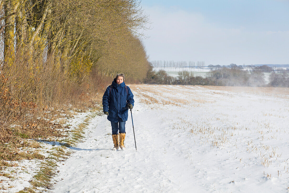 Frau beim Wandern auf schneebedecktem Feld