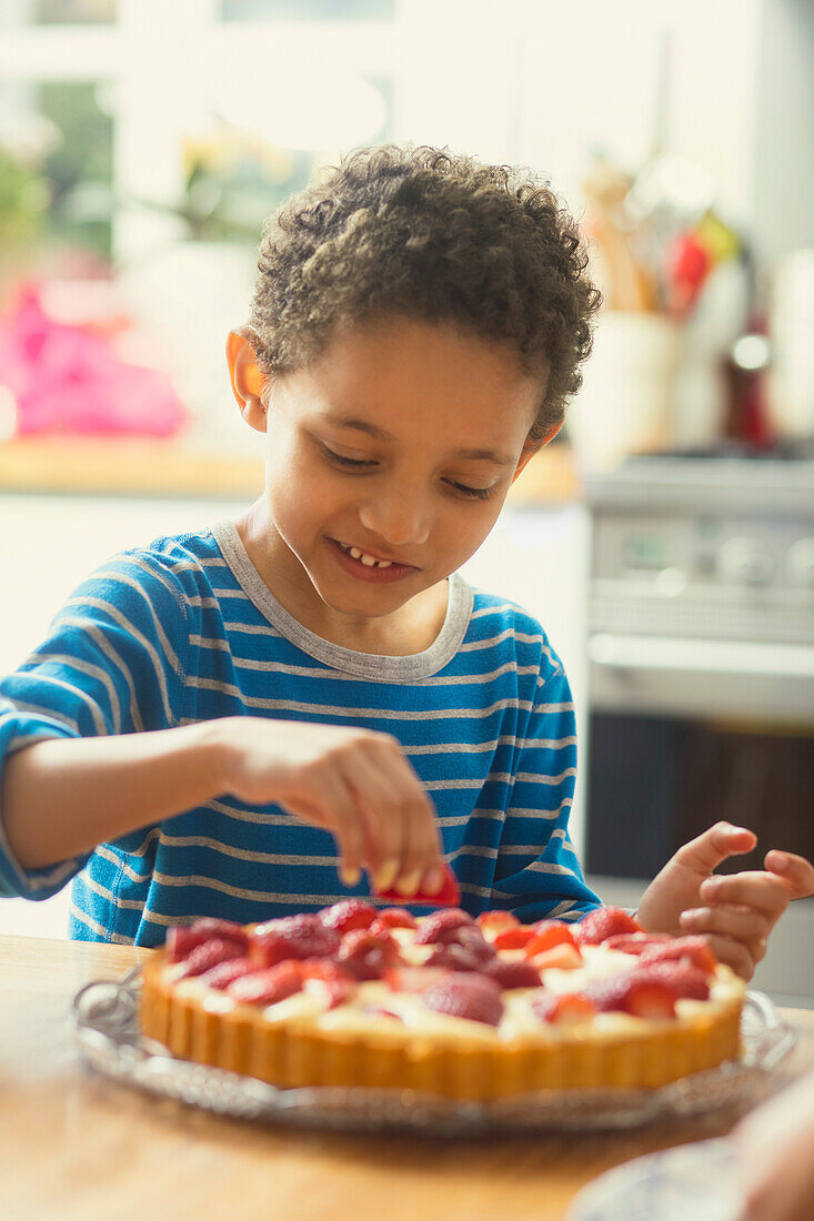 Junge gibt Erdbeeren auf den Kuchen