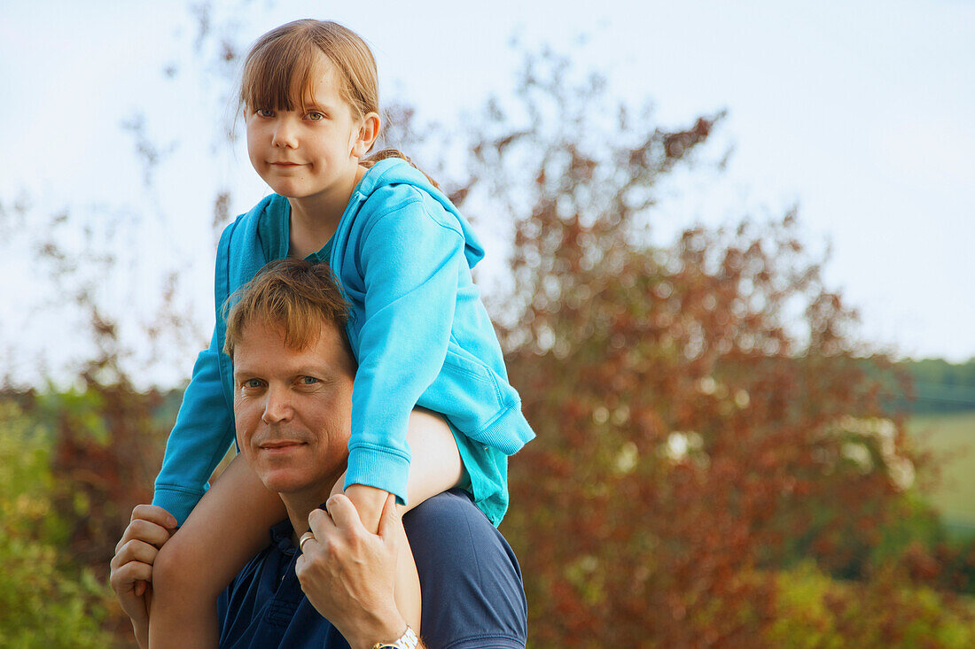 Vater trägt Tochter auf den Schultern im Freien