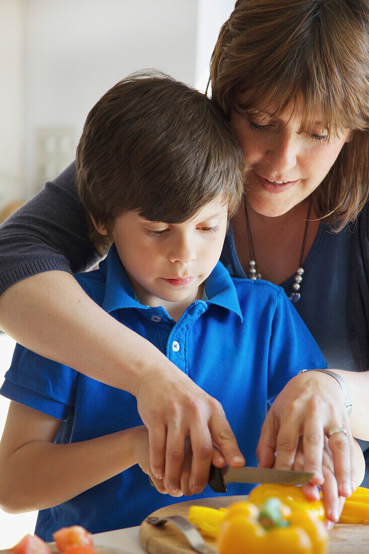 Mother and Son Cutting Vegetables in Kitchen