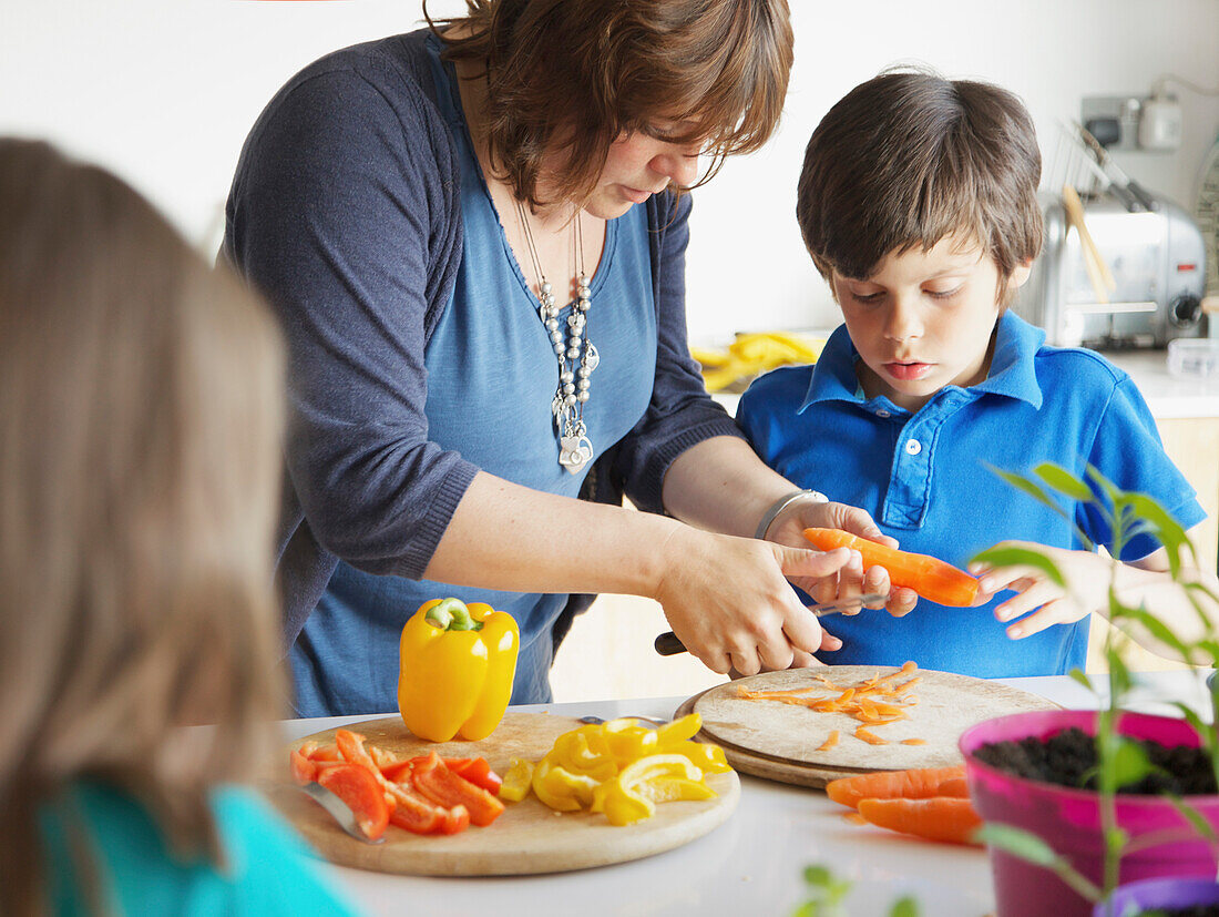 Mother and Son Cutting Vegetables in Kitchen