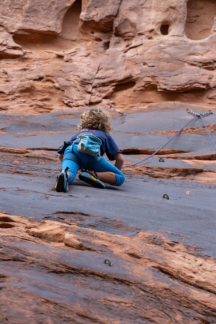 Ein 6-jähriger Junge lernt im Hunter Canyon in der Nähe von Moab, Utah, das Klettern.