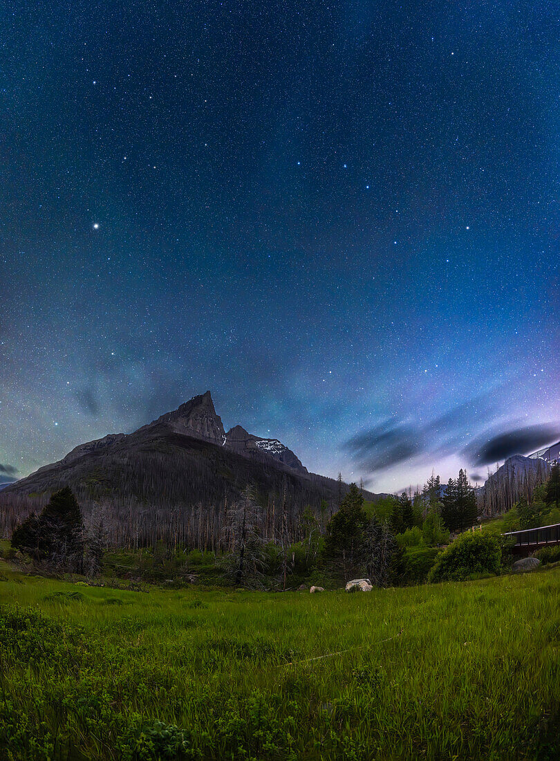 Ein vertikales Panorama des mondbeschienenen Frühlingshimmels mit dem Großen Wagen und Arkturus über dem zerklüfteten Umriss des Anderson Peak im Red Rock Canyon im Waterton Lakes National Park, Alberta, einem UNESCO-Weltnaturerbe und Schutzgebiet für den dunklen Himmel.