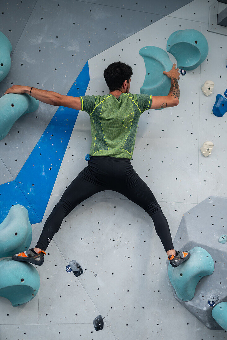 Young man in his twenties climbing on a climbing wall indoors