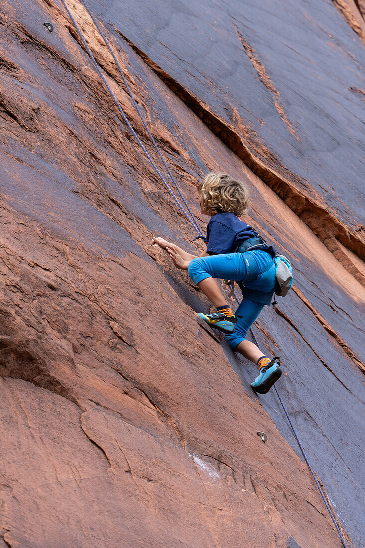 Ein 6-jähriger Junge lernt im Hunter Canyon in der Nähe von Moab, Utah, das Klettern.