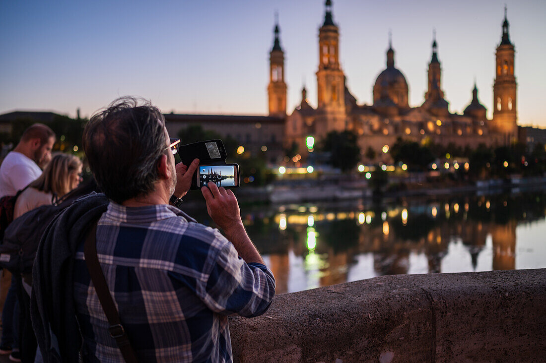 Besucher fotografieren die Kathedrale-Basilika Unserer Lieben Frau von der Säule bei Sonnenuntergang, Zaragoza, Spanien