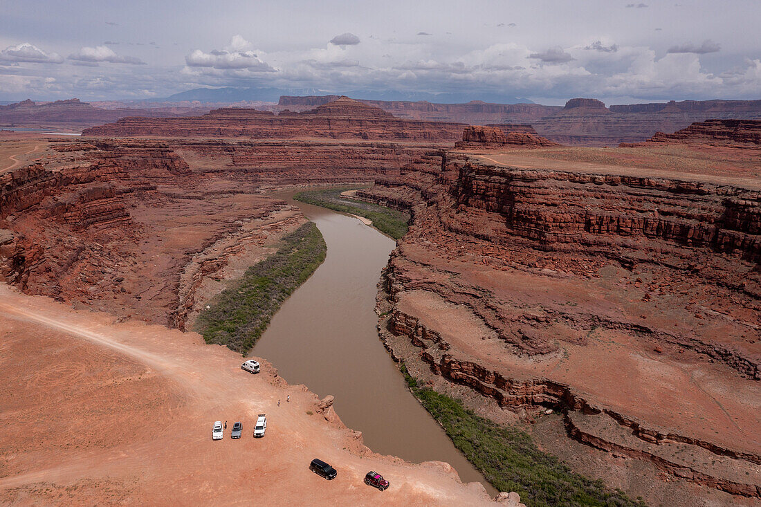 Tourists parked at Thelma and Louise Point on the Shafer Trail by the Colorado River near Moab, Utah. The official name is Fossil Point, but it is the site of the famous scene at the end of the movie, "Thelma and Louise". The Bears Ears National Monument is at right, across the river. Note: The drone was flown legally outside the boundaries of the monument.