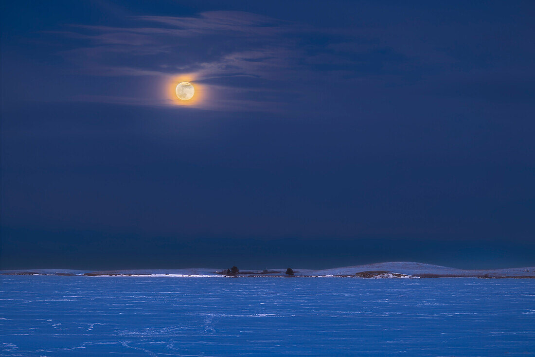 The rising of the winter "Wolf" Moon, the Full Moon of January, over the frozen Crawling Lake Reservoir, in southern Alberta, January 25, 2024. While it looks very cold, the temperature was actually a mild 0° C this night.