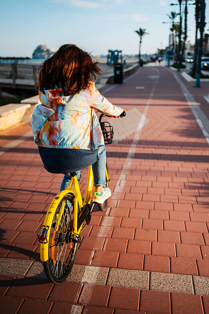 Frau fährt mit dem Fahrrad an der Promenade entlang, Peñiscola, Spanien