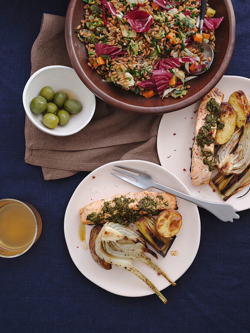 Still life tabletop view healthy Mediterranean meal of grilled salmon with pesto, leeks, spelt salad