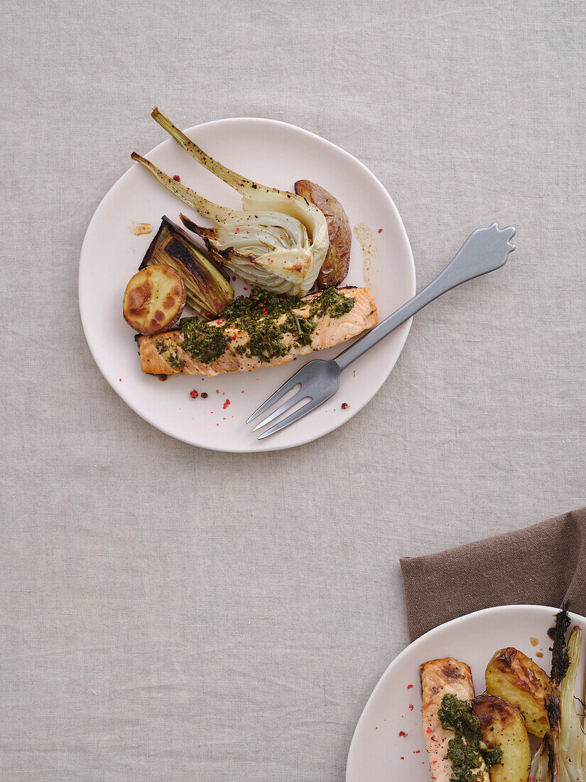 View from above gourmet meal of grilled salmon with pesto, baked potatoes, fennel and leek