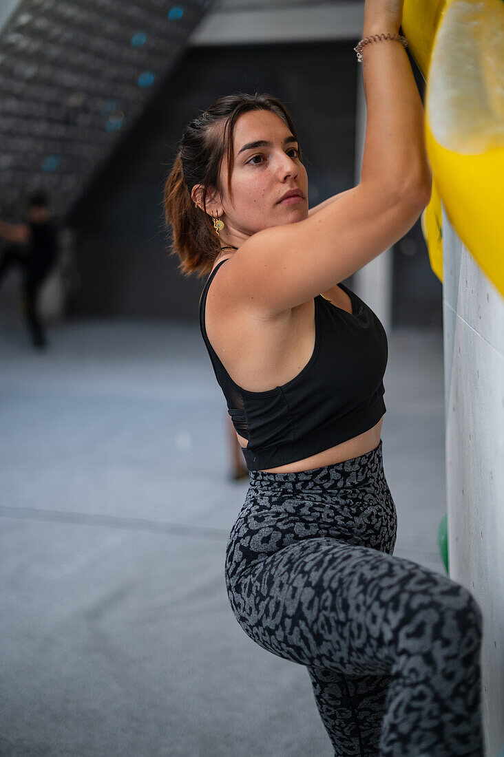 Young man in her twenties climbing on a climbing wall indoors