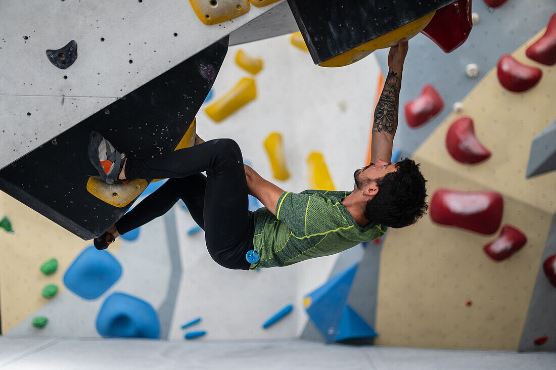 Young man in his twenties climbing on a climbing wall indoors