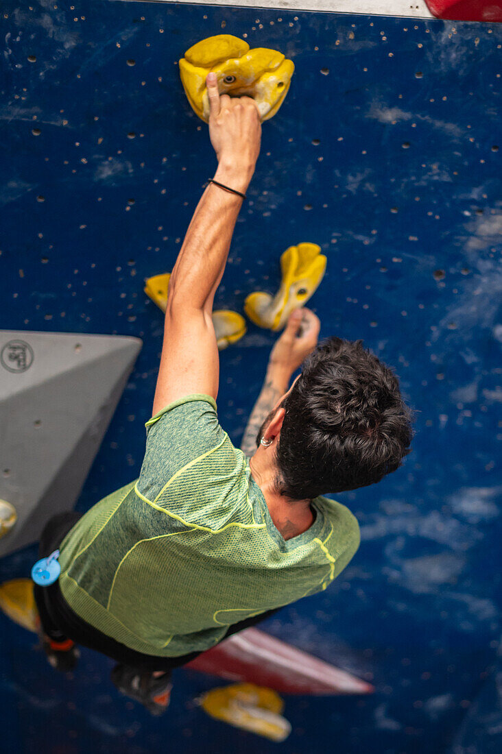 Young man in his twenties climbing on a climbing wall indoors