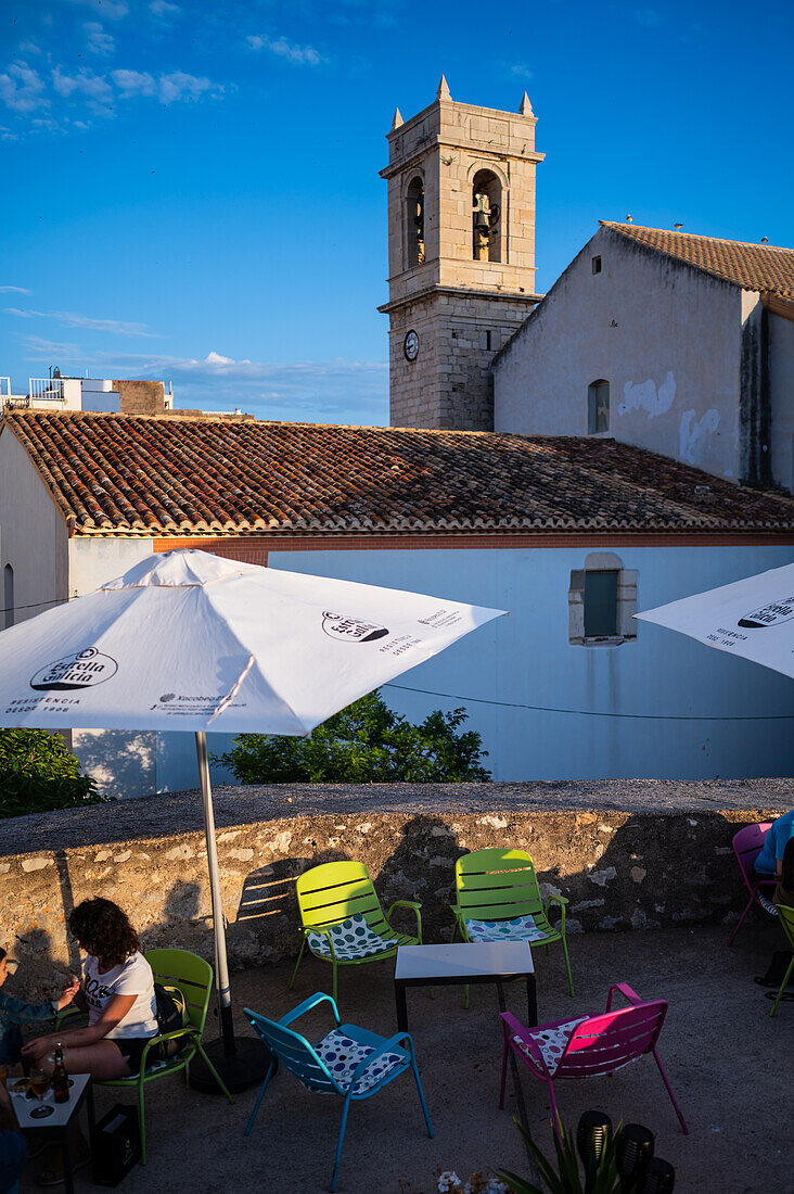 Besucher genießen den Sonnenuntergang von einem Restaurant auf der Stadtmauer der Burg Papa Luna in Peñiscola, Castellon, Valencianische Gemeinschaft, Spanien