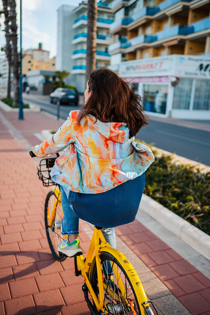 Frau fährt mit dem Fahrrad an der Promenade entlang, Peñiscola, Spanien